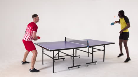 multiracial male table tennis players serving and passing the ball to each other on white background