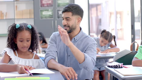 biracial girl enjoys a high-five with her teacher at school in the classroom