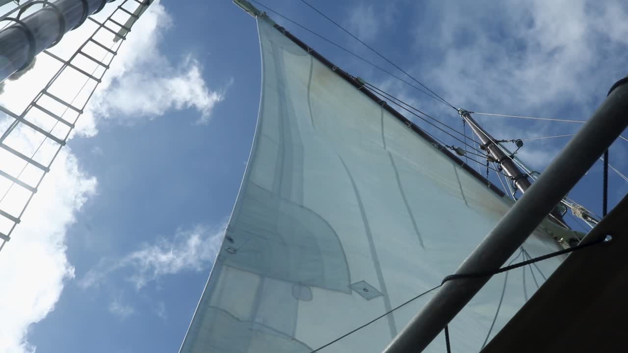 Mainsail billowing in the wind on a sunny clear day, low angle view from the deck.