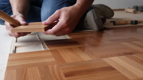 person installing wooden parquet flooring