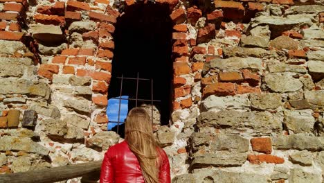 woman walking up to a ruined, red brick doorway at bauska castle, latvia