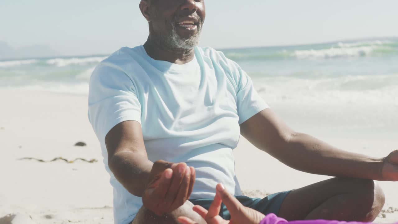 Senior african american couple practicing yoga and meditating on sunny beach