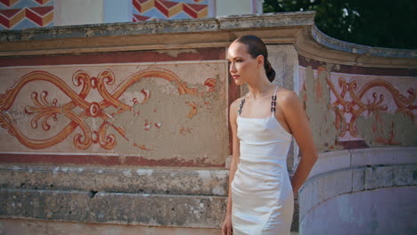 niña de pie en la pared antigua con un viejo ornamento. mujer confiada posando cerca del palacio