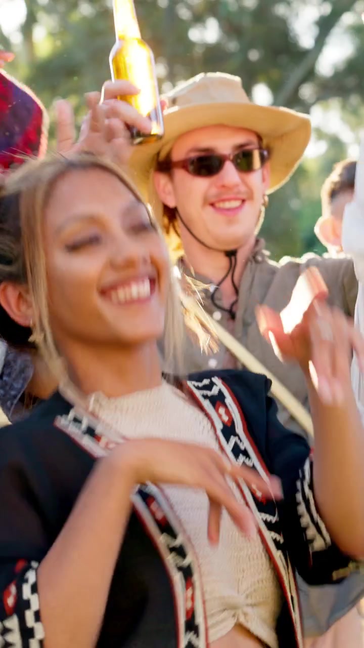 Gruppe af unge venner der danser til en udendørs musikfestival