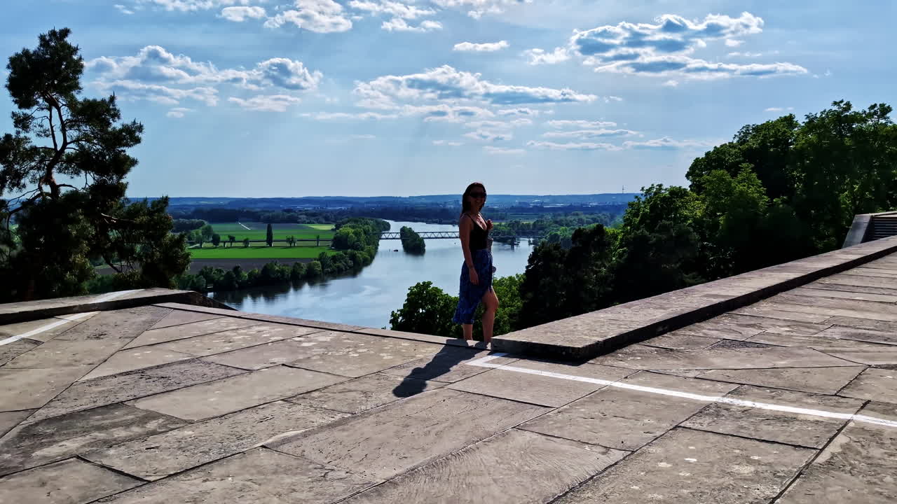 Woman standing on Walhalla terrace overlooking Danube and countryside