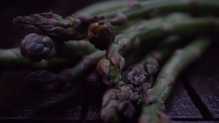 Footage of a bunch of fresh, green asparagus lying on a wood table