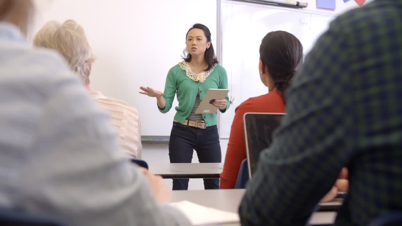 Female Asian teacher with tablet takes adult education class