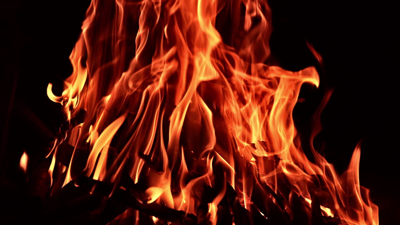 Hypnotizing bonfire burning in the dark night. Sticks of wood burn in the campfire.