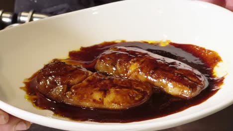 el cocinero presenta un plato de foie-gras cubierto con salsa de jerez y brandy en un restaurante español