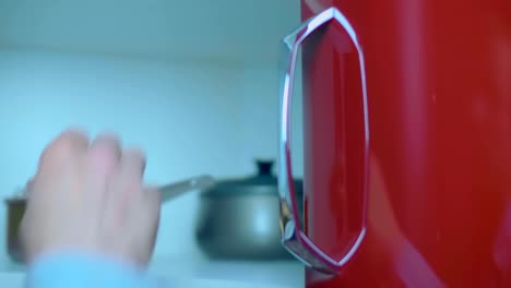 un hombre abre la puerta de un armario de la cocina y toma una sartén de metal