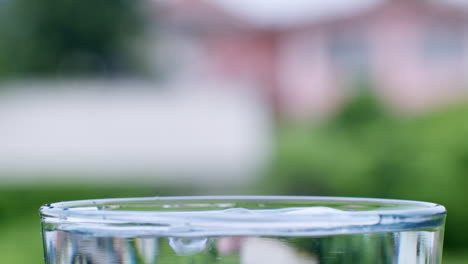 droplets of water are formed as water lands into a glass filled with clean, clear water