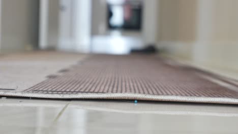 a close-up view of a rug or mat on a tiled floor, secured by a pin