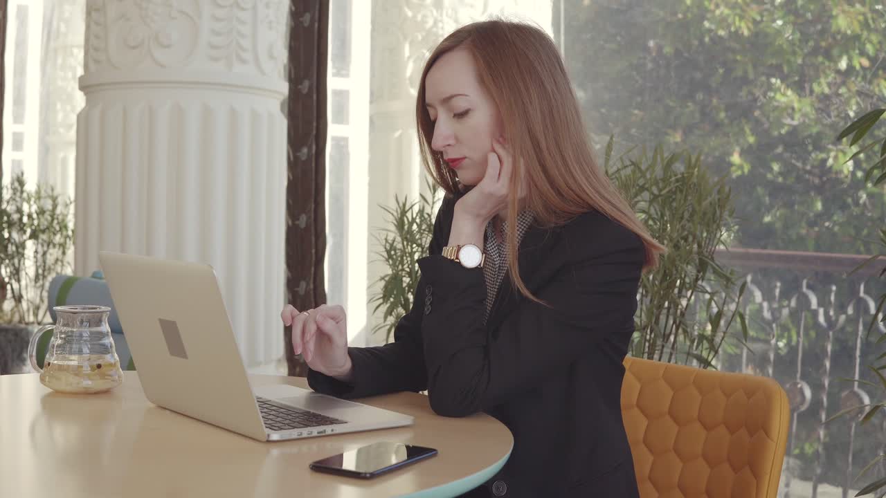 Donna d'affari che lavora al portatile in un caffè