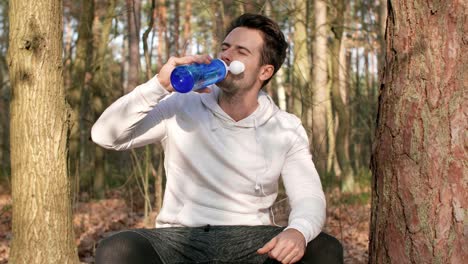 hombre cansado bebiendo agua y descansando después de un entrenamiento duro