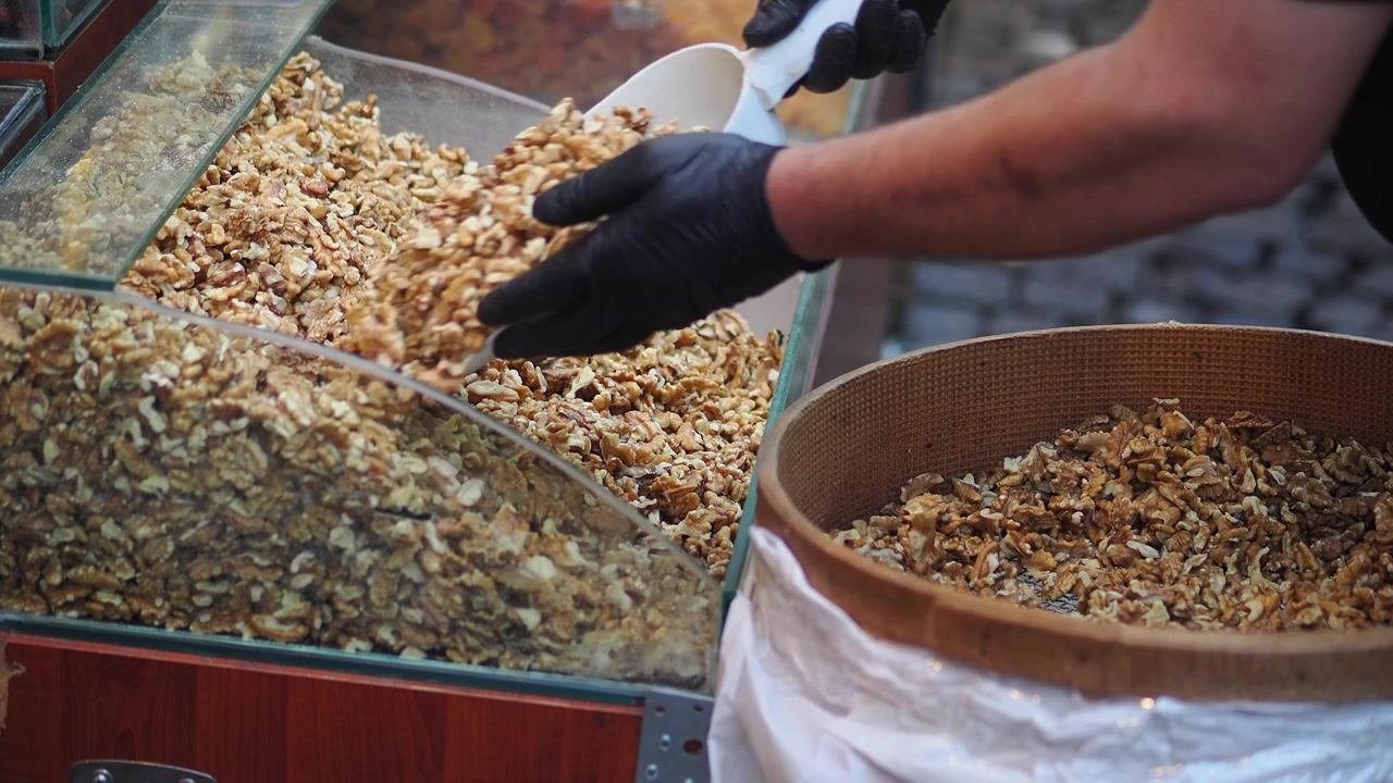 Händler schaufelt Walnüsse an einem Marktstand