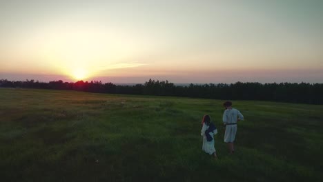 Two-people-walking-through-a-field-in-a-sunset