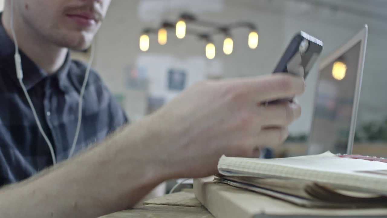 Молодой хипстер слушает музыку и работает на ноутбуке