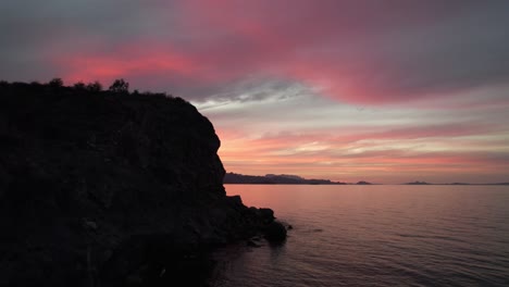 flying next to rocky cliff in the ocean during sunset in baja california, mexico