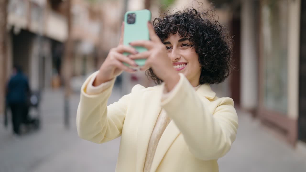 Jovem mulher sorrindo confiante fazendo selfie pelo smartphone na rua