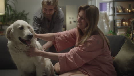 family couple petting dog on sofa at home