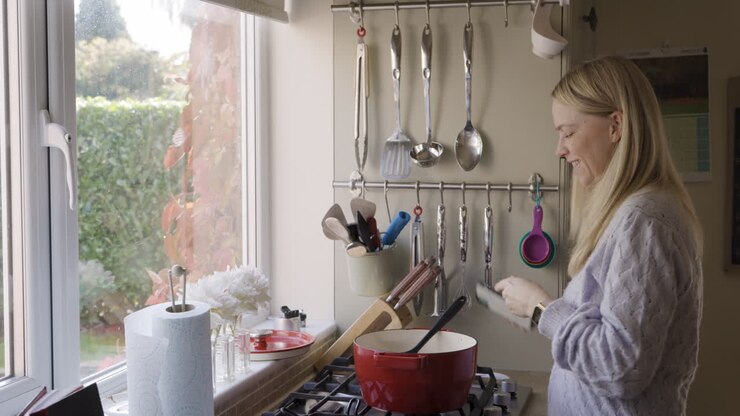 Woman using smartphone in kitchen while cooking