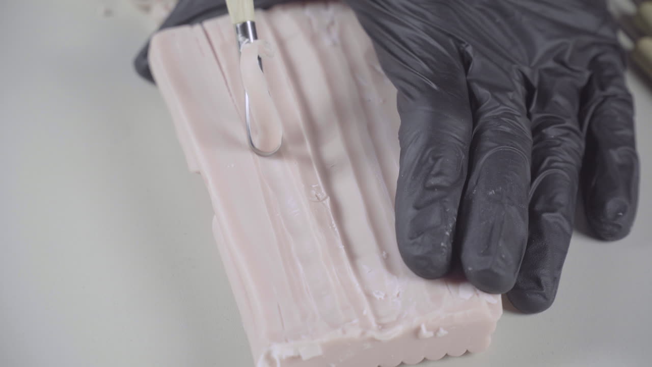 художник использует ленточный инструмент на куске пластилина, крупный план детали 4k