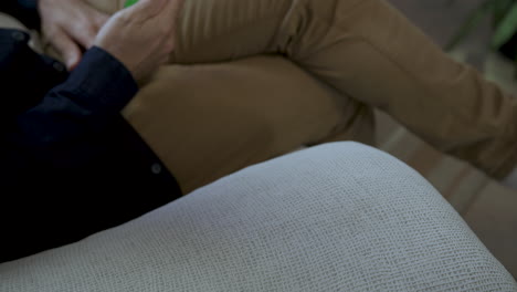 Man-Sitting-On-Couch,-Holds-Phone-With-Green-Screen-App-During-Discussion