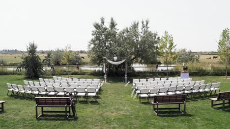 aerial drone view of empty traditional wedding ceremony set-up with archway and chairs 4k 60fps