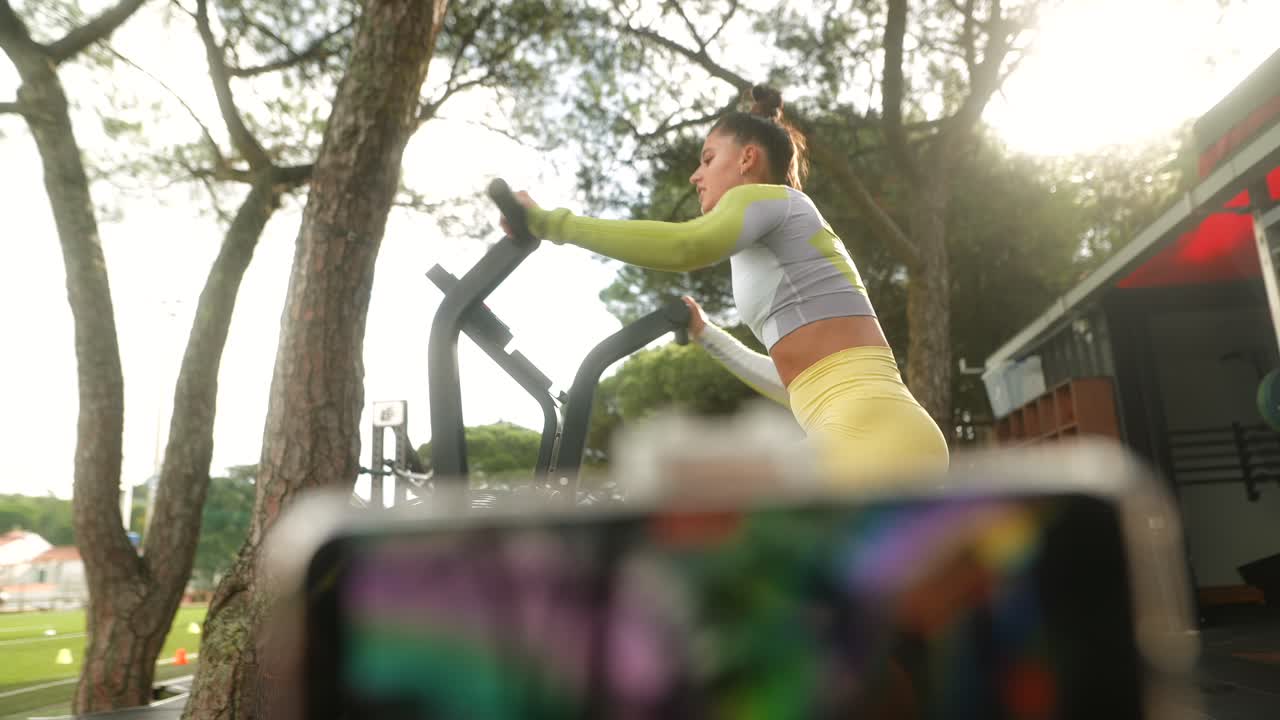Mulher em forma malhando em uma Air Bike em uma academia ao ar livre