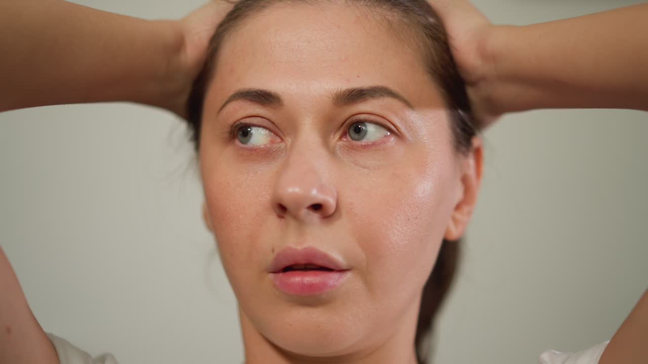 불안한 여자가 방에 서서 머리를 붙잡고, 고통스러운 감정과 싸우고, 어려움을 극복하는 방법을 찾고 있습니다.