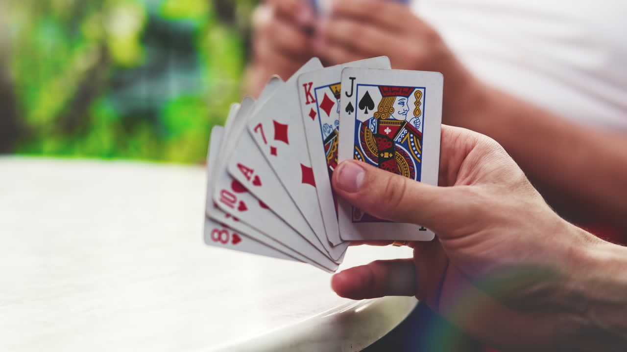 A man playing cards with other people holding a deck