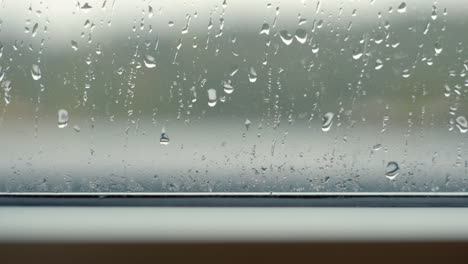 Raindrops-falling-on-clear-window-during-rain-storm-close-up