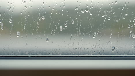 raindrops falling on clear window during rain storm close up