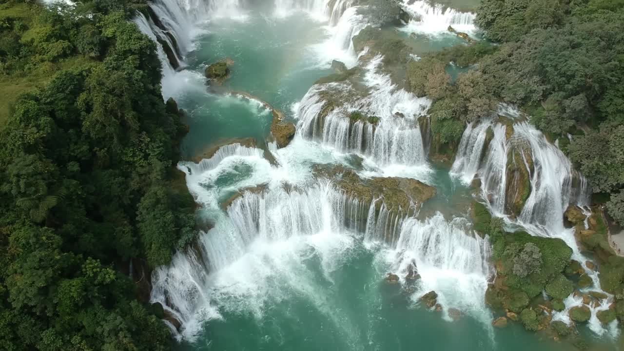 Ripresa aerea sopra le cascate a gradoni di Ban Gioc in Vietnam. Inquadratura in movimento, panoramica verso l'alto.