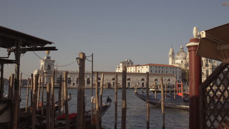 wide shot of gondolas parked in pier with wooden poles, venice, italy