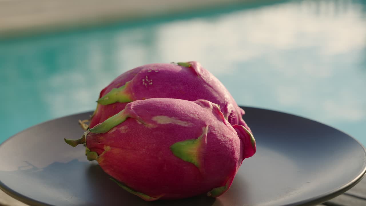 Frutto del drago su un piatto con piscina sullo sfondo al tramonto durante l'ora d'oro.