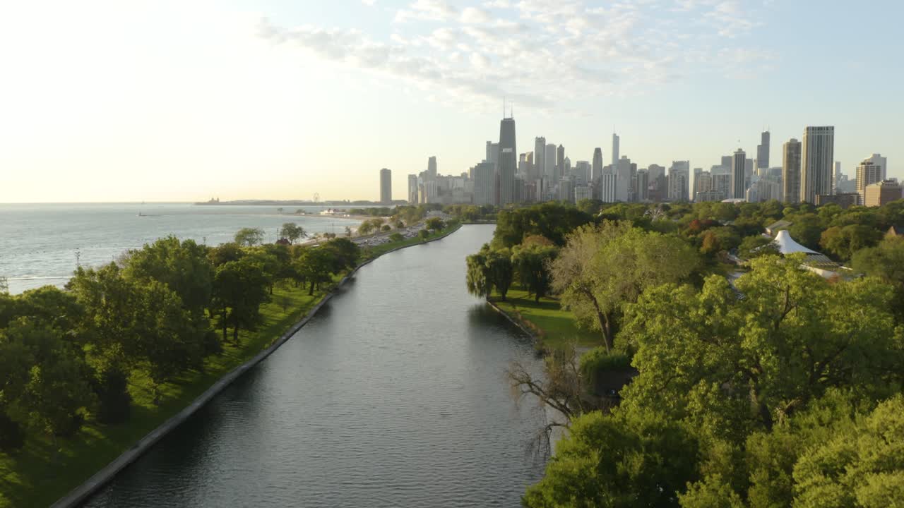 Drone stiger op for at afsløre Chicagos skyline, Lincoln Park og Lake Michigan under en smuk sommersolnedgang.