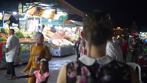 girl walking through night markets in marrakesh morocco exploring the local culture, busy crowds with lots of people