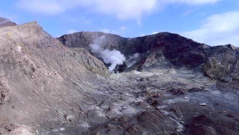 cráter volcánico de isla blanca con humo distante en ascenso, aéreo
