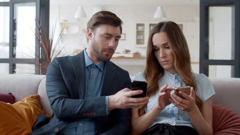Business-couple-surfing-internet-on-smartphones.-Man-showing-news-on-mobile
