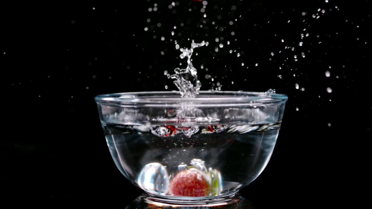 Fragola rossa fresca cade in una ciotola piena d'acqua, vista in ultra rallentatore