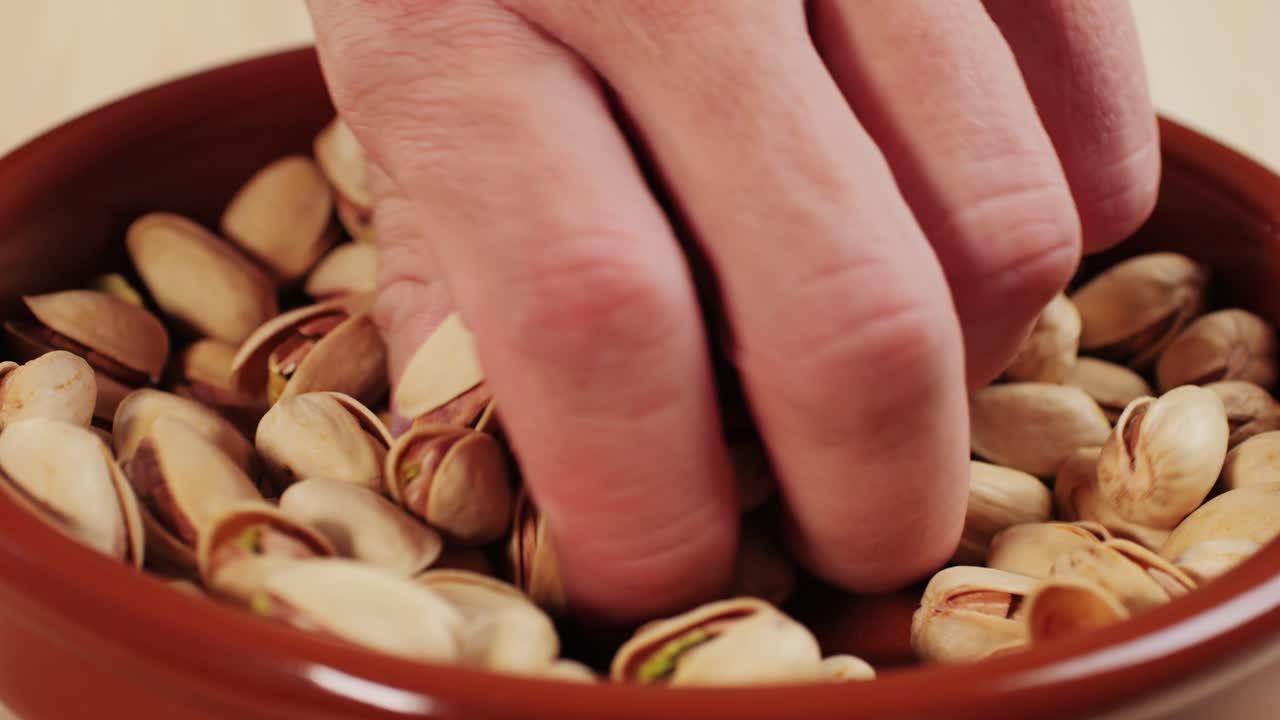 Salted pistachios on plate close-up macro. Nuts snacks for parties, fried crispy pistachios with cracked shells for beer . High quality 4k footage