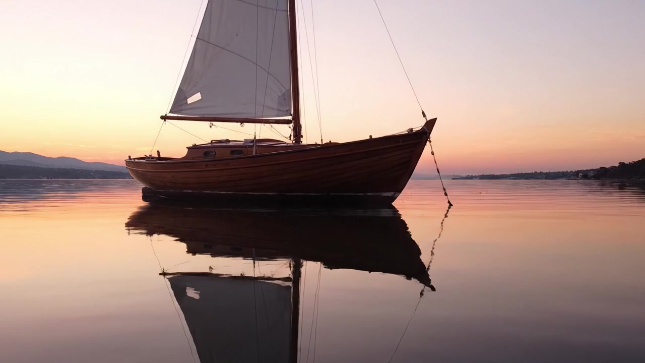 Serenità al Crepuscolo: Una Barca a Vela di Legno Scivola Silenziosamente Sulle Acque Calme, Riflettendo i Bellissimi Colori del Tramonto in un Paesaggio Marino Pacifico