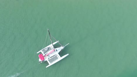 Large-white-boat-slow-movement-on-dark-green-water-to-meet-the-sun-at-sunset,-top-view-of-the-boat-4k-video