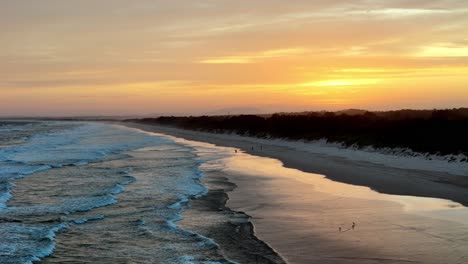 Das-Frühe-Licht-Der-Morgendämmerung-Taucht-Den-Strand-In-Warme-Farbtöne,-Sanfte-Wellen-Streicheln-Das-Ufer