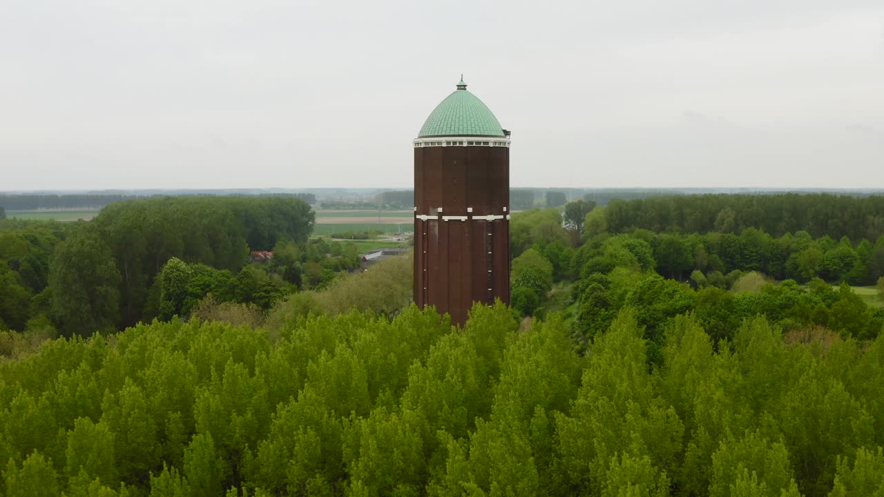 Aerial approach to the famous water tower in the city of Axel shot on a cloudy day with lots of surrounded trees
