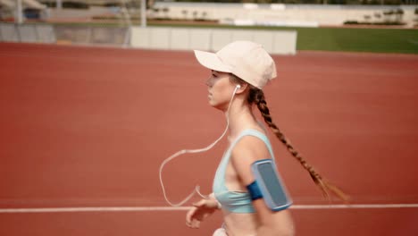 active woman running on sports track and listening to music