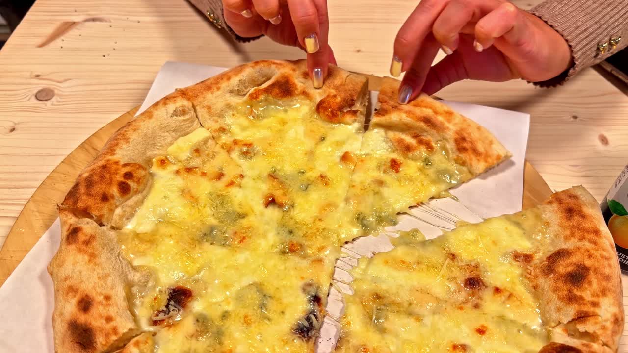 Primo piano dall'alto di una fetta di pizza al formaggio presa da una mano femminile.