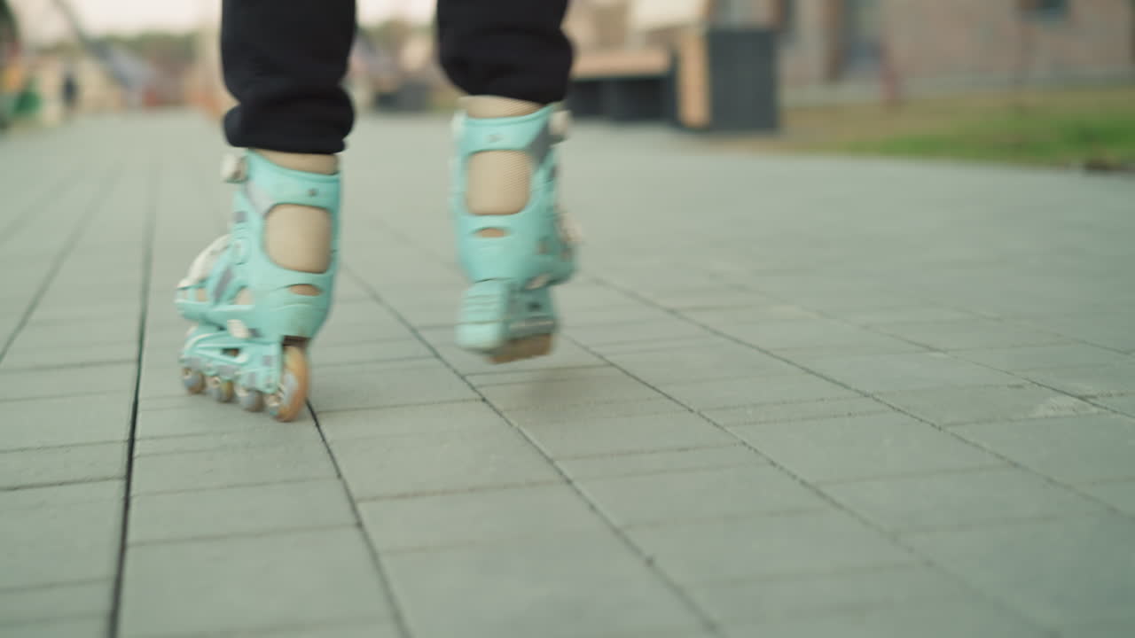 롤러블레이드가 공원에서 포장된 경로에서 부드럽게 미끄러지는 동적 근접 촬영 롤러브레이드 바가 표면 위로 굴러가는 것에 초점을 맞추는 야외 스케이팅의 움직임과 에너지