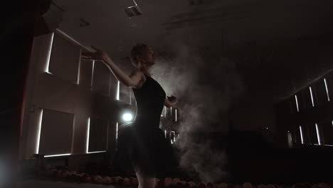 SLOW-MOTION.-unrecognizable-beautiful-ballerina-performing-on-dark-smoke-stage.-Blonde-woman-with-hair-in-black.-Ballet-dress-dancing-with-hands